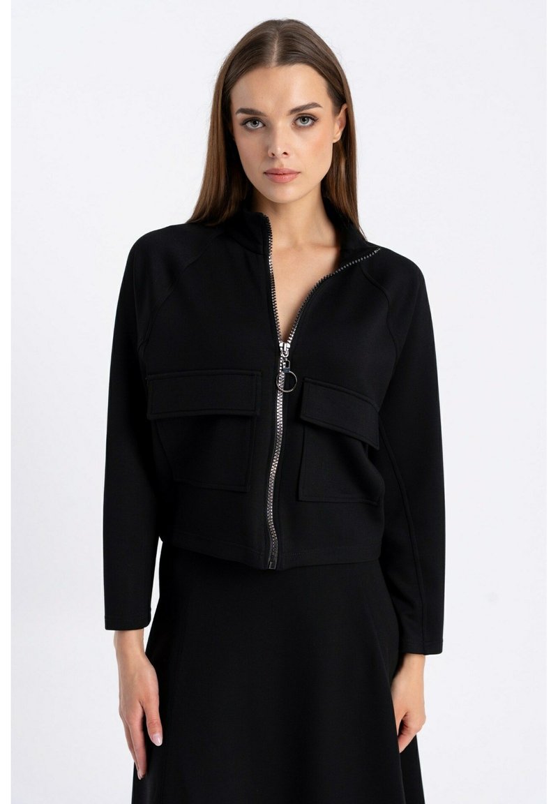 Czarna krótka kurtka zapinana na zamek z gładkiego materiału, posiadająca dwie kieszenie z przodu i wysoki kołnierz. Projekt zawiera srebrny zamek błyskawiczny i minimalne detale.