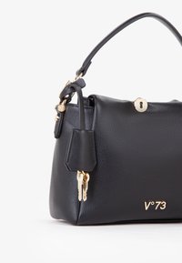 Bolso de mano de cuero negro con un acabado texturizado, herrajes dorados, charm de llave y un logo grabado en la parte frontal. Compacto con una forma estructurada.