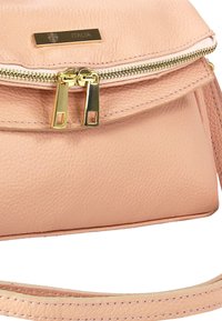 Perzikkleurige leren handtas met een getextureerde afwerking, gouden beslag, dubbele ritsen en een plaatje met de tekst "ITALIA." Voorzien van een smalle schouderband.