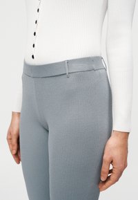 Γκρι ριμπ κολάν με εφαρμοστό σχέδιο, λείο ζωνάκι μέσης και διακριτικές ραφές. Το υλικό φαίνεται μαλακό και ελαστικό.