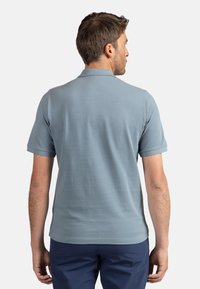 Polo shirt azzurro chiaro a maniche corte in cotone, con colletto classico. Tessuto morbido con dettagli di cucitura discreti sulle maniche.