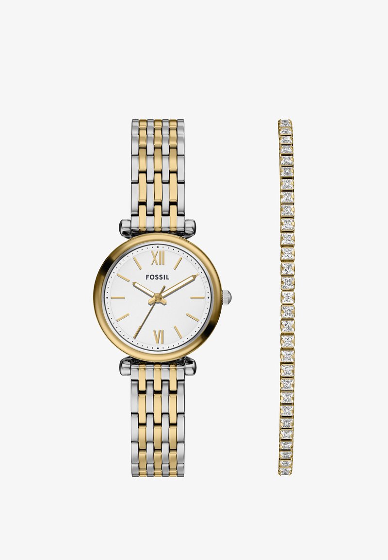 Fossil ur med en tofarvet metalrem i sølv og guld, rund hvid urskive, guld timerindikatorer og et matchende guldarmbånd med krystaller.