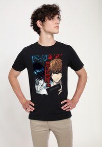 Czarny bawełniany T-shirt z kolorową grafiką dwóch postaci z "Death Note" wraz z tekstem i wzorem z postrzępionym brzegiem.