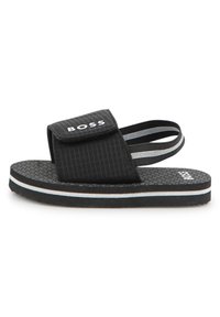 Μαύρο σανδάλι με υφασμάτινο επάνω μέρος με υφή, ρυθμιζόμενο λουράκι και αναπαυτική σόλα. Διακοσμημένο με λευκές και γαλάζιες οριζόντιες ρίγες.