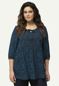Blusa blu navy con motivo paisley, dotata di maniche a tre quarti, dettagli arricciati e scollatura a chiave con nastro. Tessuto morbido.