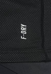 Black activewear fabric with a textured, perforated pattern. Features white "F-DRY" logo. Smooth finish with elastic seams.