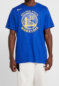 Modré bavlněné tričko s logem Golden State Warriors ve žluté barvě, uprostřed číslo "30". Krátké rukávy, kulatý výstřih.