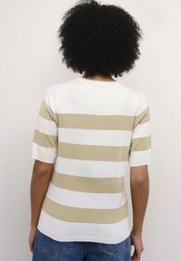 Beige en wit gestreepte trui met korte mouwen, een ronde hals en een gestructureerde afwerking, gedragen met blauwe denim shorts.