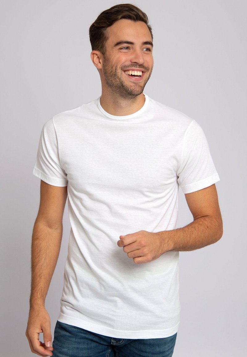 Witte katoenen t-shirt met een ronde hals en korte mouwen, met een gladde textuur en een ontspannen pasvorm. Draagt met blauwe jeans.