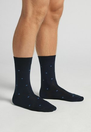 Calcetines azul marino con una textura suave, con pequeños puntos azules. Puños acanalados y un diseño clásico de longitud de tripulación.