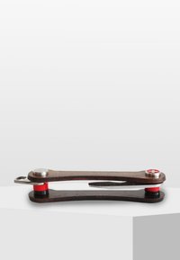 Mångsidigt verktyg med en mörk träkropp, silvermetallaccenter och röda gummispetsar, med en snygg, böjd design och en slank profil.