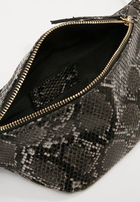 Pouch con motivo di pelle di serpente nero e grigio, con un esterno testurizzato, cerniera dorata e interno di tessuto nero. Include una piccola tasca interna.