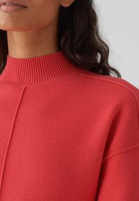 Maglione rosso lavorato a maglia con un collo alto a coste, realizzato in un tessuto dalla trama interessante e con un design a vestibilità rilassata con cuciture sulle spalle.