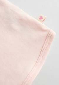 Tela de color rosa claro con una textura suave, que presenta un dobladillo cosido y una pequeña etiqueta con un diseño de corazón.