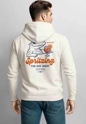 Helle Hoodie in Cremefarbe mit einem verspielten Grafikdesign, das ein Cartoon-Krokodil zeigt, das einen Cocktail hält, und dem Text "Spritzing THE DAY AWAY" in Fettschrift.