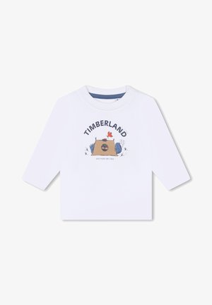 Witte langliggende T-shirt met lange mouwen, voorzien van een grafische print met "TIMBERLAND", een kampeerscène en kleurrijke cartoon elementen. Drukknopen op de schouder.