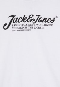 Bijela pamučna majica s crnim otisnutim logotipom "Jack & Jones" i dodatnim tekstom ispod u manjem fontu. Klasični okrugli izrez.