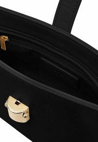 Interno di una borsa a tracolla nera in pelle con un gancio in metallo dorato e una tasca con zip. Texture liscia e linee di design pulite.