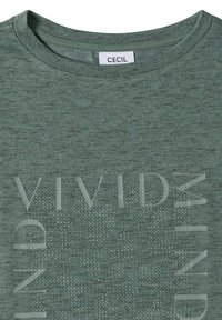 T-shirt vert texturé à col rond avec des lettres en relief et des détails en perles formant l’inscription « VIVID MIND » et une étiquette de la marque CECIL à l’intérieur du col.