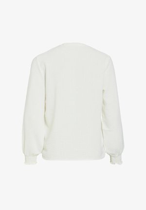 Bílá texturovaná halenka s dlouhým rukávem, elastickými manžetami a mírně volným střihem, zobrazena zezadu na jednobarevném pozadí.