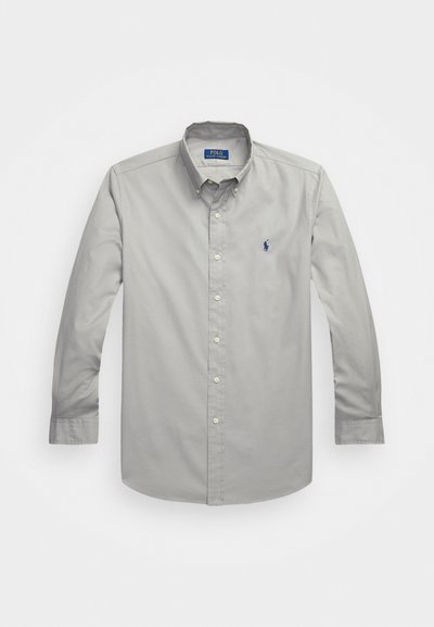 Camicia a maniche lunghe di cotone grigia chiara, con colletto classico, chiusura frontale con bottoni e un piccolo ricamo blu.