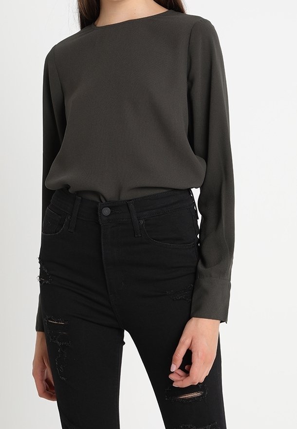 Long-sleeve, dark green blouse with a crew neck, paired with black distressed jeans featuring ripped details and a high-waisted fit.