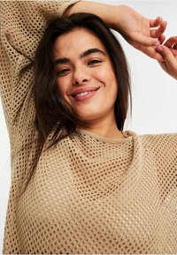 Beige gestrickter Pullover mit lockerem, offenen Netzdesign. Verfügt über einen weiten Ausschnitt und Dreiviertelärmel, mit einer weichen Textur.