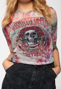 Graphic crop top featuring a tie-dye pattern in pink and green, with a skull design surrounded by roses and text in red and black.