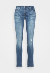 Jeans skinny de mezclilla azul con un lavado claro, que presentan un ligero desvanecimiento y áreas desgastadas, diseño tradicional de cinco bolsillos y cierre de cremallera.