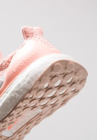 Różowy but do biegania z teksturowaną dzianinową cholewką, gładką gumową podeszwą środkową oraz wzorzystą podeszwą z okrągłymi wypustkami zapewniającymi przyczepność.