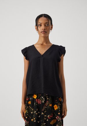 Black, sleeveless top with a V-neck and ruffle accents. Soft, textured fabric with a loose fit. Worn over a floral-patterned skirt.