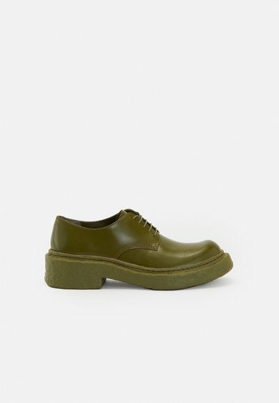 Zapatos de cuero verdes con cordones, suela de plataforma gruesa, punta redonda y detalles de costura mínimos. Textura suave con un acabado brillante.