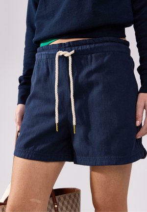 Pantaloni corti blu navy realizzati in cotone, con vita regolabile tramite un cordoncino in beige con estremità di metallo dorato e tasche laterali.
