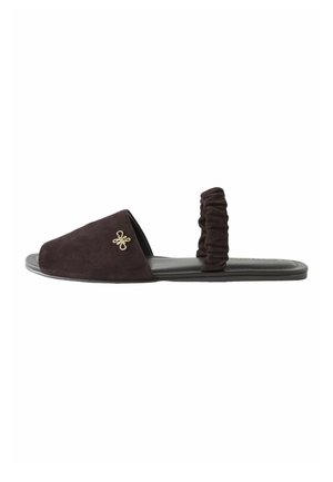 Flat black suede slide sandal with ruched back strap and gold decorative logo on closed toe section.