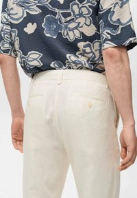 Lichtbeige linnen broek met een rechte snit, voorzien van twee achterzakken met knoopsluitingen en een gladde, textuurstof.