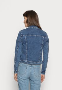 Jeansjacka i mellanblått, med en figursydd design och sömdetaljer samt en klassisk krage, ihop med ljusblå jeans.