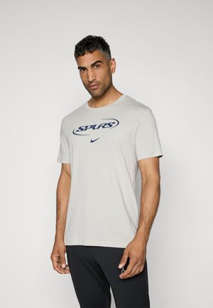 Light gray T-shirt with a round neckline, featuring a navy blue "SPURS" graphic and Nike logo on the front. Short sleeves, cotton fabric.