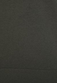 Tissu tricoté vert foncé avec une texture côtelée à l'ourlet. Le tissu est uniformément tissé, présentant une surface lisse.