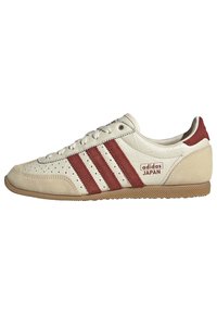 Muške Adidas Japan tenisice s bijelim kožnim gornjim dijelom, crvenim prugama, perforiranim detaljima i gumenim potplatom.