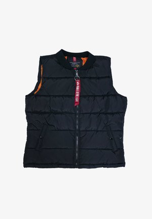 Black quilted sleeveless vest with front zipper and red fabric pull tab reading "Remove Before Flight," orange inner lining visible at armholes.