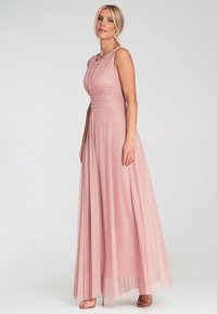 Langes pinkes Abendkleid mit plissierter Oberseite, tailliertem Schnitt und fließendem Rock. Es hat einen weichen, durchsichtigen Stoff und dezente Details.