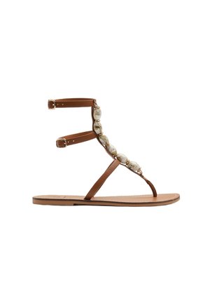 Flad brun lædersandal med ankelstropper, tå-loop og store beige marmorerede perleudsmykninger langs den forreste rem.