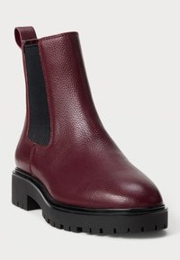 Burgundy nahkatossu nilkkamallia, jossa on joustavat sivupaneelit, pyöristetty kärki ja paksu musta kumipohja, jossa on uritusta.