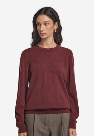 Burgundy tröja med rund halsringning, ribbade ärmmuddar och nederkant; tillverkad av mjukt texturerat material; i kombination med ljusgrå, veckade byxor.