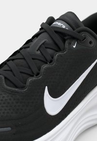 Juodas sportinis batas su tekstūruotu audiniu, apvaliu nosiu, sintetine balta Nike swoosh emblema ir kruopščiai suprojektuotais raišteliais.