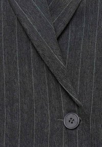 Blazer a spina di pesce grigio scuro con righe verticali a contrasto, dotato di un bottone nero e rever affilati. Tessuto testurizzato con un design classico.