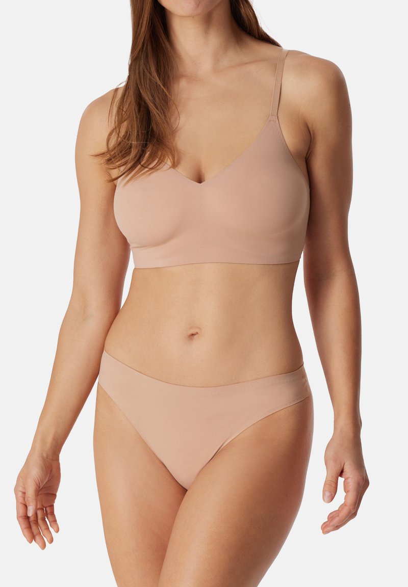 Lys beige sømløs bh med tynde stropper og V-hals-design, kombineret med matchende bikinitrusser. Glat, strækbart stof.