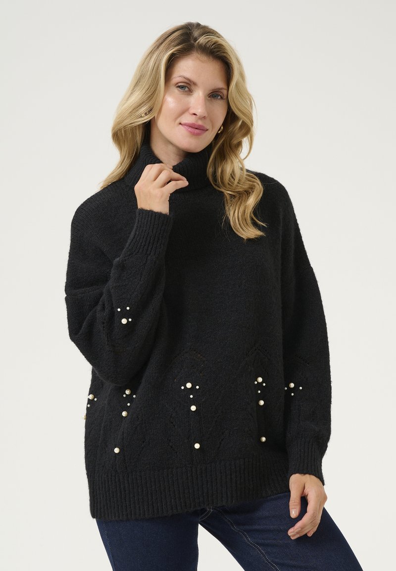Svart stickad polotröja med lös passform. Inkluderar pärl-accenter och texturerade diamantmönster på den nedre delen. Ribbstickade ärmslut och nederkant.