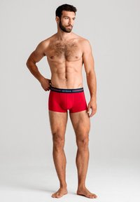 Röda boxerkalsonger gjorda av stretchtyg med ett marinblått elastiskt midjeband som pryder märkesnamnet "ombre." Fitted design, slät textur.