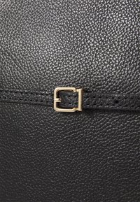 Black textured leather bag with a smooth finish. Features a gold-colored clasp and subtle stitching detail on the edge.